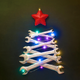 A Christmas tree made of overlaying wrenches, decorated with lights and a sparkly red star ornament on top on a plane green background